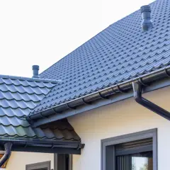 Szary dach z dachówki ceramicznej, idealny do obliczenia dachówka ceramiczna cena za m2. System rynnowy odprowadza wodę.