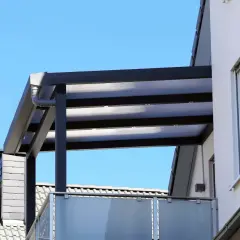 Nowoczesne zadaszenie balkonu w bloku, zgodne z przepisami, chroni przed słońcem i deszczem.