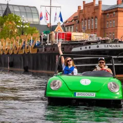 Para wodna w Bydgoszczy, na wodzie zielony samochodzik z parą turystów, na statku wielkie litery "BYDGOSZCZ". Idealne bydgoszcz wydarzenia kulturalne.