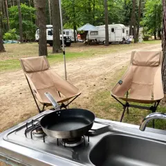 Gotowe do gotowania na kempingu! Dwa wygodne krzesła, kuchenka i zlew czekają na posiłek.
