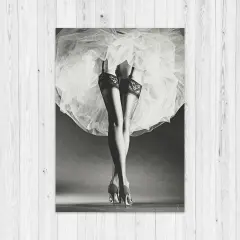 Nogi w pończochach i szpilkach, ukryte pod zwiewną spódnicą. Klasyka w stylu Horst P. Horst.