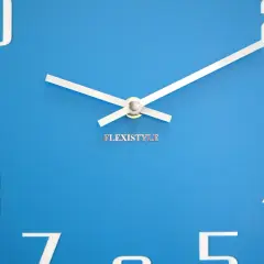 Niebieski zegar ścienny z białymi cyframi i wskazówkami. Na tarczy widnieje napis "FLEXISTYLE".