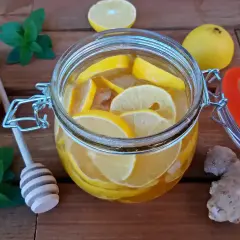 Słoik z plastrami cytryny i imbirem, idealny do przygotowania orzeźwiającej wody imbirowej. Przepis na zdrowy napój.