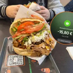 Pyszny kebab w Mustafas Gemüse K w Berlinie kosztuje 15,80 €. Obok rachunku widać świeże składniki i mięso.