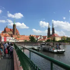 Mosty i katedra to to, z czego słynie Wrocław. Ludzie spacerują po moście, podziwiając widok na rzekę i zabytkową architekturę.