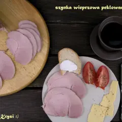 Pyszna, pieczona szynka wieprzowa, pokrojona w plastry, podana z pieczywem, pomidorami i serem. Idealna na śniadanie.