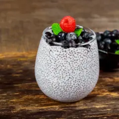 Pudding chia z jagodami i maliną. Nasiona chia – właściwości i przeciwwskazania. Zdrowy deser na drewnianym tle.