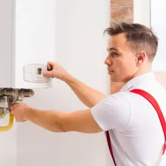 Tecnico esegue verifica caldaia, controllando i collegamenti e il pannello di controllo.