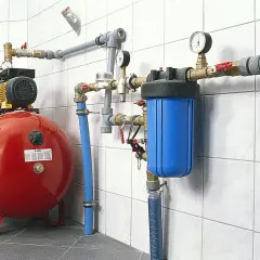 System hydroforowy z pompą, czerwonym zbiornikiem i niebieskim filtrem wody. Rury i złączki pex tworzą skomplikowaną instalację.