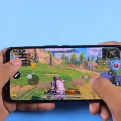Ręce trzymają smartfon, na którym widać dynamiczną rozgrywkę z jednej z najlepszych gier android. Akcja toczy się w malowniczej, górskiej scenerii.