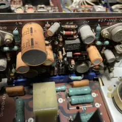 Wnętrze starego urządzenia elektronicznego z widocznymi kondensatorami, rezystorami i tranzystorami. Jeden z kondensatorów ma oznaczenie 220uF, a obok niego widać potencjalny problem z dc offset.