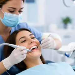 Dentista esegue pulizia dei denti. La paziente sorride, nonostante la paura che la pulizia dei denti fa male.