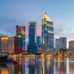 Ho Chi Minh Miasto nocą, z lśniącymi wieżowcami odbijającymi się w wodzie.