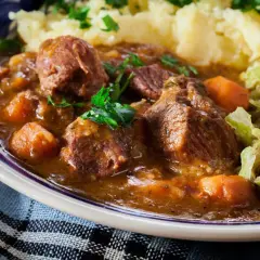 Un plat réconfortant de navarin d'agneau, avec des morceaux de viande tendres, des carottes et une sauce savoureuse, servi avec de la purée et du chou. Une recette parfaite pour un repas familial.
