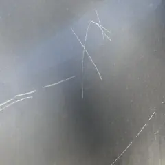 Zarysowania na ciemnym lakierze samochodu, widoczna klapka paliwa.