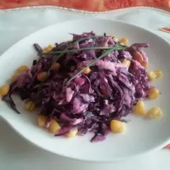 Wykwintna surówka z czerwonej kapusty jak w restauracji, z dodatkiem kukurydzy i szczypiorku, podana na białym talerzu.