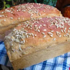 Dwa bochenki domowego chleba posypane słonecznikiem, idealne do nauki jak upiec chleb w domu.