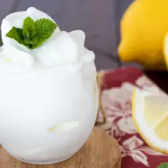 Sorbetto al limone fatto in casa, fresco e profumato, guarnito con menta. Accanto, limoni freschi e una tovaglietta rossa.