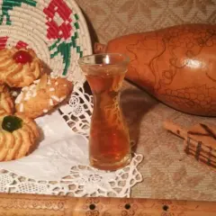 Biscotti decorati, un bicchierino di vernaccia di Oristano, una zucca intagliata e un flauto in legno.
