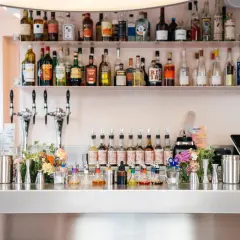 Bar à cocktails prêt à servir, avec des bouteilles d'alcool sur les étagères et des sirops colorés sur le comptoir. Les "bisous bisous club reviews" sont excellentes pour ce bar !