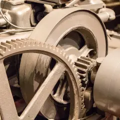 Metalowe koła zębate, w tym duża zwolnica, tworzą skomplikowany mechanizm napędowy.