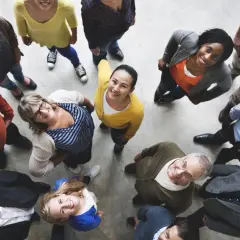 A diverse group of people smiles up at the camera, perhaps after a successful local government event.