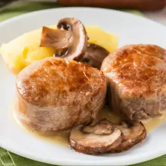 Dwa soczyste medaliony z polędwicy wieprzowej z pieczarkami i puree ziemniaczanym. Idealna temperatura dla polędwicy wieprzowej to 63°C.