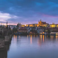 Nastrojowa fotografia nocna Pragi z Mostem Karola i zamkiem na wzgórzu.