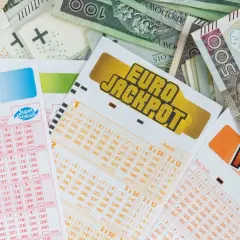 Kupony Lotto i Eurojackpot leżą na stosie banknotów. Zastanawiasz się, ile jest do wygrania w Eurojackpot dzisiaj?