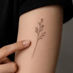 Ein zartes Zweiglein-Tattoo, ein feines striche tattoo, ziert den Arm.