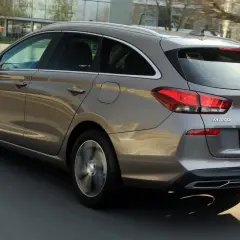 Szary Hyundai i30 1.6 CRDi kombi jedzie po drodze, widać jego tylną część i bok.