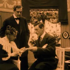 Scen från tidiga art movies: en kvinna tar emot ett brev från en man, medan en annan man står bakom.