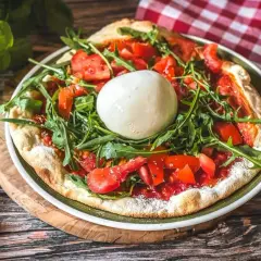 Pizza mit frischen Tomaten, Rucola und einer Kugel Burrata, die Lust auf burrata selber machen macht.