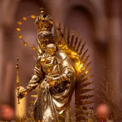 Goldene Statue der Maria mit Kind, gekrönt und von Strahlen umgeben. Die Bedeutung von Maria wird hier durch ihre königliche Darstellung und die Verehrung deutlich.