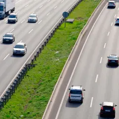 Varios coches circulan por la autopista. Un camión blanco lidera el tráfico. ¿Es correcto este adelantamiento?