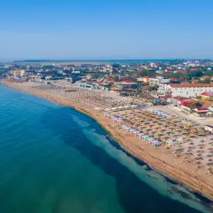 Plaża nad Morzem Czarnym z rzędami leżaków i parasoli. W tle zabudowania kurortu. Woda wygląda na ciepłą, idealną do kąpieli.