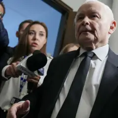 Starszy mężczyzna w garniturze, otoczony przez dziennikarzy z mikrofonem TVP Info, być może odpowiada na pytanie: co złego zrobił PiS?