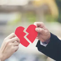 Dwie dłonie trzymają połówki złamanego czerwonego serca. Symbolizuje to ciągłe kłótnie z mężem i rozpad związku.
