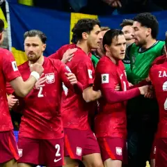 Piłkarze w czerwonych strojach z orzełkiem na piersiach, świętujący sukces. Polska drużyna walczy o mistrzostwa świata.