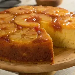 Un délicieux gâteau à l'ananas, renversé et caramélisé, avec une tranche coupée pour révéler sa texture moelleuse.