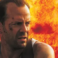 Bruce Willis i en actionfylld scen, med eld bakom sig. En klassisk bild från filmer med Bruce Willis.