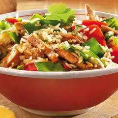 Schüssel mit Reis, Fleischstreifen, Paprika und Erbsen. Ein köstliches Gericht aus der Wok-Küche, garniert mit Koriander.
