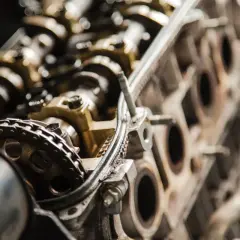 Widok na wnętrze silnika samochodowego, gdzie widać fragment łańcucha rozrządu i metalowe elementy.