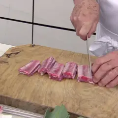 Chef corta costillas de cerdo en trozos para una deliciosa terrina de costilla.