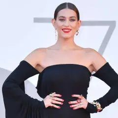 Gaia, la cantante, posa con un abito nero elegante e gioielli vistosi.