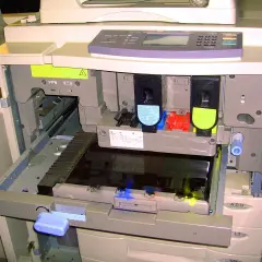 Wnętrze drukarki z widocznymi tonerami i mechanizmem.