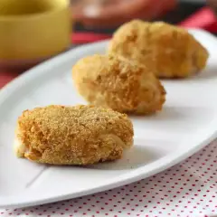 Trois croquetas espagnoles dorées et croustillantes sur une assiette blanche.