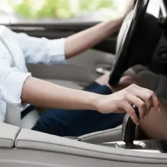 Dłoń kobiety na dźwigni zmiany biegów, przygotowująca do jazdy. Adaptacja skrzyni biegów w nowoczesnym samochodzie.