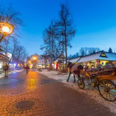 Wieczorny spacer po Krupówkach, gdzie zakopiańskie centrum kultury tętni życiem. Konny zaprzęg i oświetlone kramy tworzą magiczny klimat.