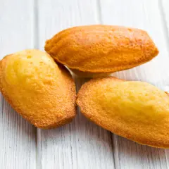 Trois madeleines dorées sur fond de bois clair, parfaites pour une recette de madeleines salées pour apéritif.